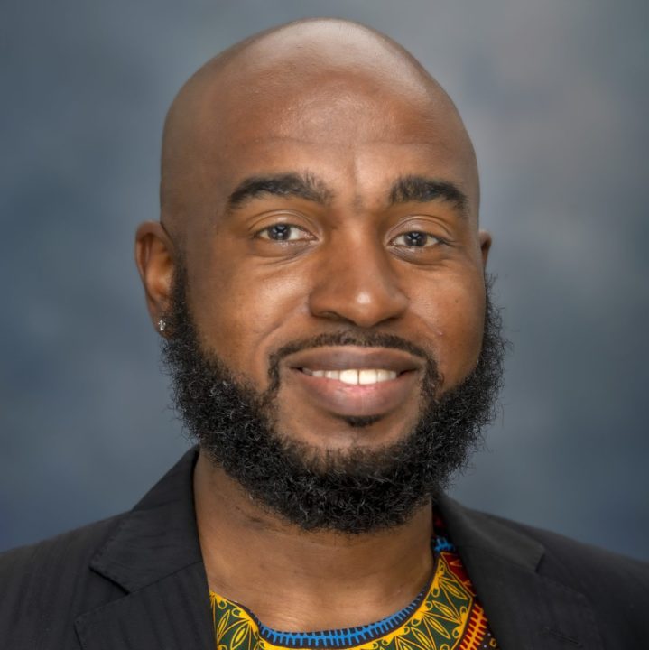 headshot of Julian, a Black man with a beard and bald head