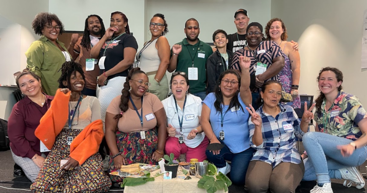 A group of fifteen individuals of different races and genders pose joyfully